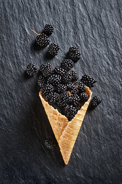 Blackberry explosion. Photo of blackberry in waffle cone on black slate. Top view. High resolution product.