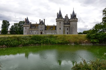 Fototapeta na wymiar Castle of Sully-sur-Loire, Loire region, France. Snap of 30 June 2017 at 18:21. Captured at the entrance of the castle park. White clouds moving on blue sky. Towers well visible in the image.