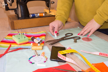 Seamstress hands on the work table with measuring tape. Tailor hands working with scissor and suit textile cloth