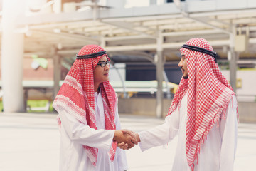 Two  Arabian businessman smile and shaking hands after meeting and over deal their agreement to sign agreement or contract.