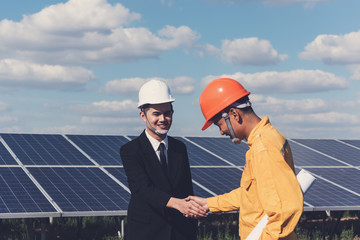 Two  Electrical engineers smile and shaking hands after meeting and over deal their agreement or contract during checking and repairing, fitting  photovoltaic plant in solar power station