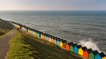 Beach huts hit by a wave at the West Cliff Beach in Whitby, North Yorkshire, UK