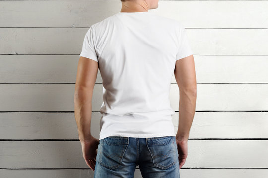 Mockup    T-shirts on a young athletic guy on a white wooden background.