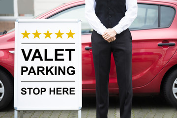 Young Male Valet Standing Near Valet Parking Sign