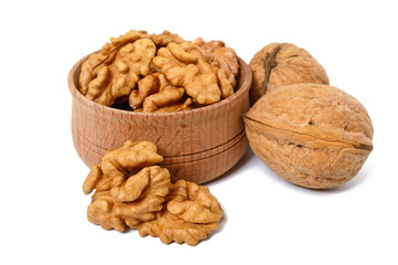 Walnuts kernels in a wooden bowl and whole nuts isolated on white background.