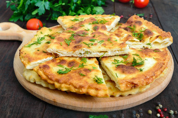 Khachapuri with cheese on a dark wooden table. Traditional Imeretian tortillas. Georgian national cuisine.