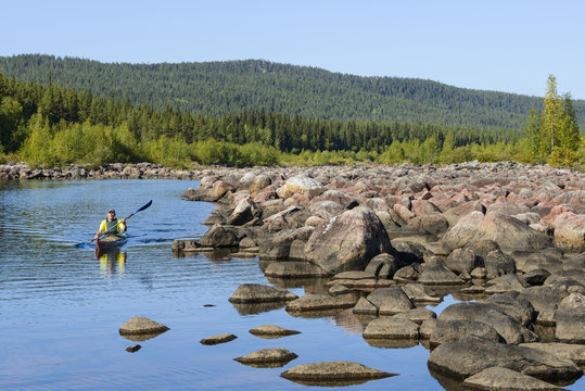 Person kayaking near rocky lakeshore