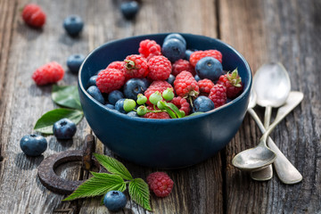 Juicy blueberries and raspberries on old wooden rustic table