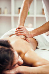 Obraz na płótnie Canvas Young man is having back massage on spa treatment.