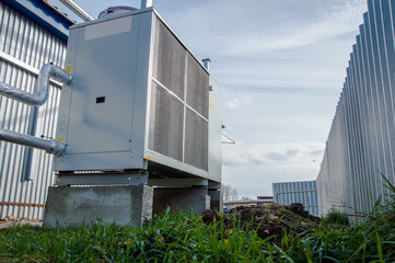 Low angle view of the gray commercial chiller standing outdoor on the ground near to the modern...