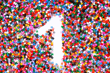 Frame in the shape of number one. Background of multicolored decorative plastic craft beads.  