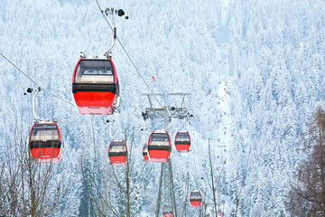 Red gondola car lift on the ski resort over forest trees © rilueda