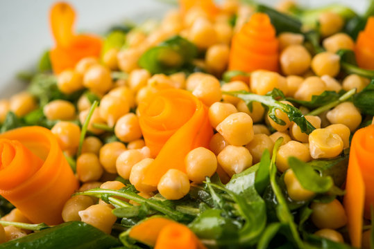 Close up of salad with arugula and chickpea decorated with carrot flovers