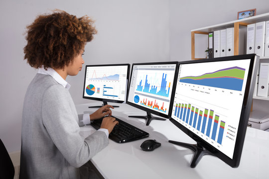 Businesswoman Analyzing Graph On Multiple Computers