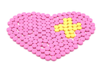 Pink pill is heart shaped and Yellow pills are placed in a cross shape. Creative healthcare and medicine concept  isolated on white background .