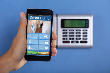 Person Holding Mobile Phone With Home Security Application