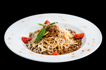 Pasta with meat, tomato and cheese in a white plate isolated on black background