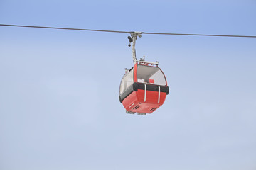 Red gondola car lift on the ski resort against blue sky