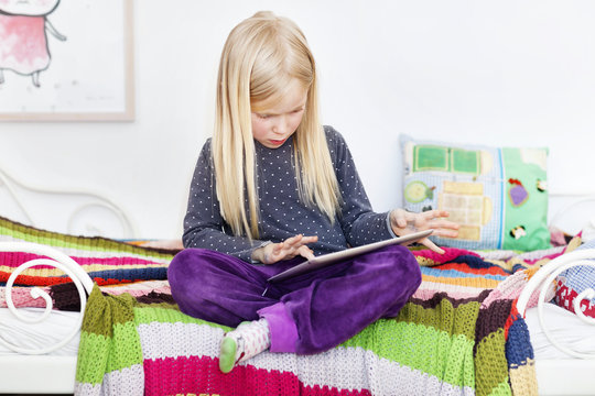 Girl sitting on bed using tablet