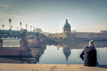 Saint-Pierre Bridge reflecting in Garonne river and Dome de la Grave with a young student in...