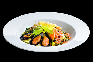 Fresh seafood salad with prepapred clams, shrimp and lemon in a white plate isolated on black background