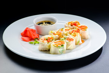 Fresh Vegetable Spring Rolls with soy sauce and ginger in a white plate, isolated on black background