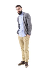 Handsome hipster in smart casual clothes posing tilted with hands in pockets. Full body length portrait isolated on white studio background. 