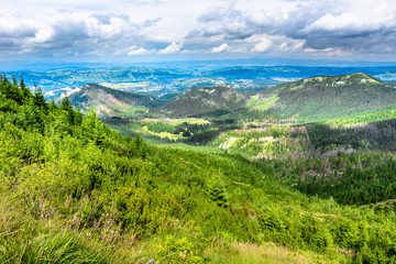Green valley and hills in mountains with city panorama, mountain landscape