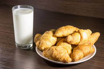 Glass of milk and fresh croissants on wooden table