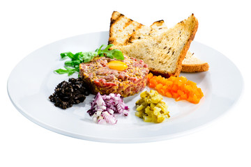 Tasty Beef Tartare with egg yolk, croutons and salad in a white plate isolated on white background, close-up