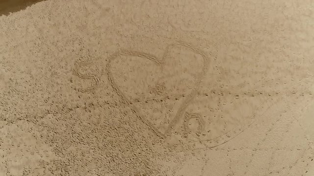 Aerial top-down view of heart beach drawing  and the letter S and N indicating S loves N background aerial footage for summer love or vacation love beautiful not too quiet beach summer scene 4k
