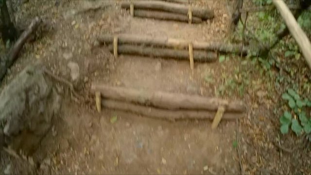 A man climbs the mountain path and clings to the railing.