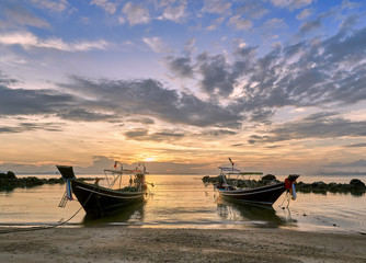 Island beach with a long tail boats at colourful sunset background