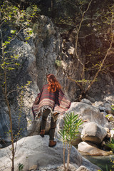 Female traveler in poncho standing on the rock in Turkey