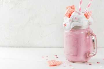 Crazy shake, romantic milkshake for Valentine's day with strawberry, white chocolate and sugar candy hearts, on white background, copy space