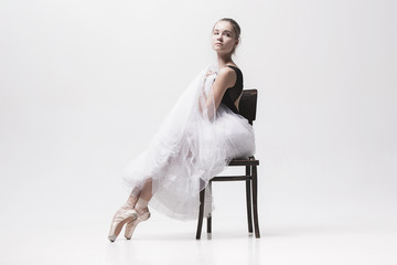 The teen ballerina in white pack sitting on chair