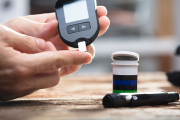 Person Checking Blood Sugar Level With Glucometer