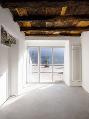 Empty room with large windows and antique beams