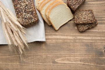 Cutted slices and whole grain fitness bread on a wooden board. Rural food. Top view.
