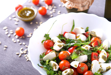 Fresh green salad with arugula, tomatoes and mozzarella  with pesto sauce