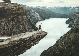 Man jumping on Trolltunga rocky cliff edge in Norway mountains Travel Lifestyle adventure happy emotional concept extreme journey vacations outdoor above clouds