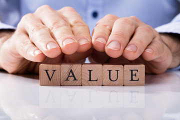 Human Hand Over Wooden Block With Value Text