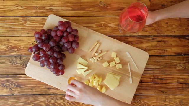 Slate board with various cheese and a glass of red rose wine.