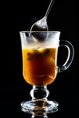 Process of preparing hot Buttered Becherovka cocktail with honey, cinnamon and anise on dark background
