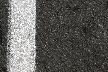 Closeup of road surface with white paint line, vertical.