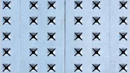 Brutal background of light perforated steel. X-shaped holes in the iron sheet. Wide photo for the website slider..