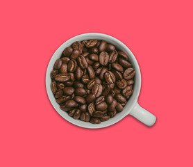 White coffee cup filled with coffee seeds isolated on pink background.