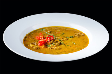 Tasty chili soup with basil in a white plate isolated on dark background. Traditional Italian cuisine