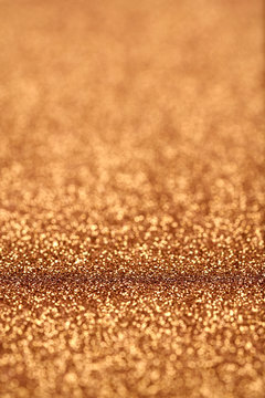 Portrait image at 45 degree angle of gold glitter background iwith blur