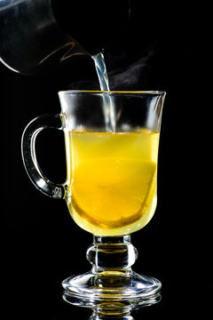 Process of preparing hot grog with lemon and honey with steam on dark background